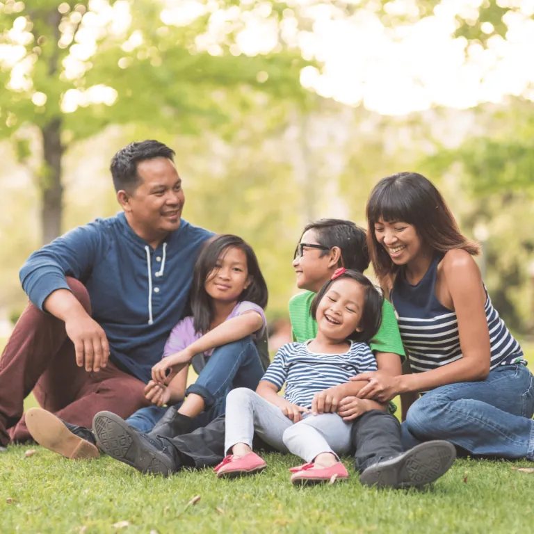 family photo sitting on grass laughing